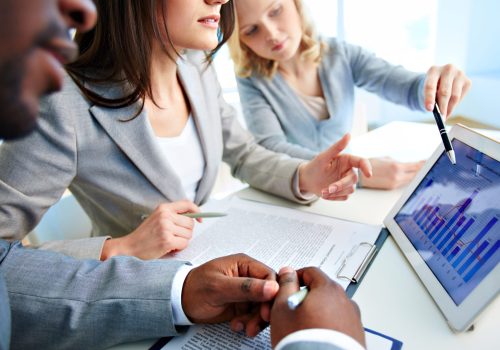 Close-up of young businesswomen discussing document in touchpad